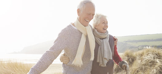 pareja mayor paseando entre dunas cerca de una playa