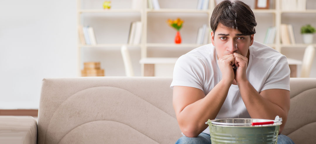 Persona preocupada con goteras en su casa