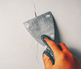 Persona reparando una grieta de la pared