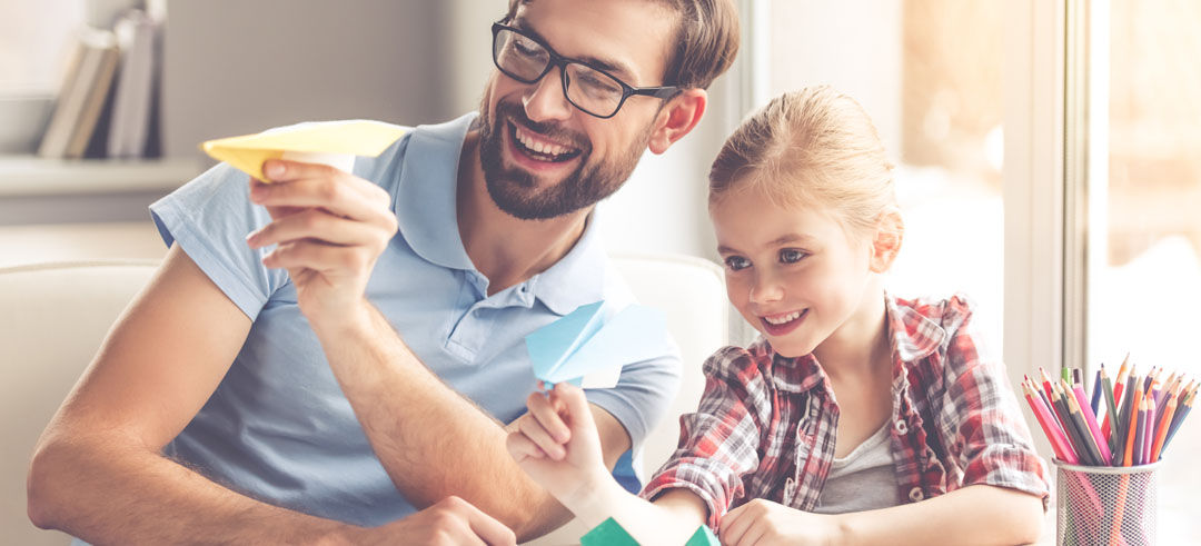 Padre e hija jugando haciendo volar dos aviones de papel