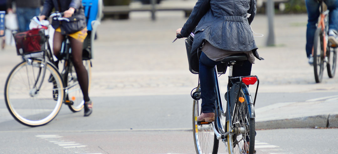 Dos personas en bicicleta cruzando un paso de peatones por el carril bici