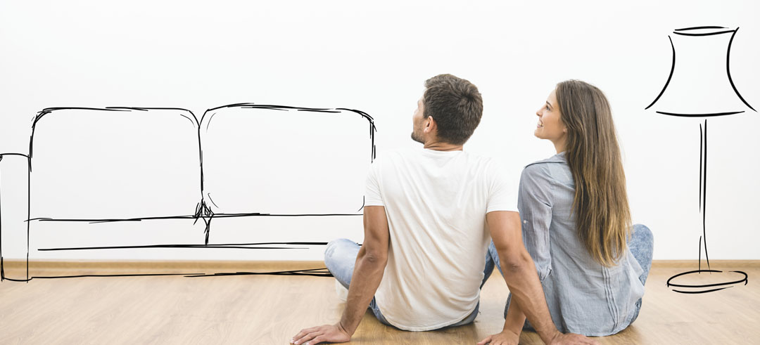 Pareja sentada en el suelo mientras se imaginan muebles de su casa